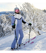 A woman wearing a light purple and white jacket with black accents and a front zippered closure, on the mountain.