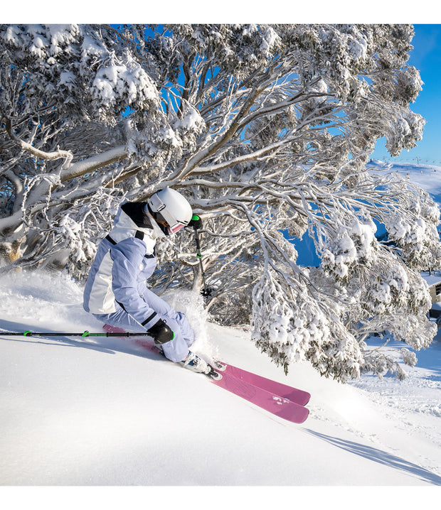 A woman ski in a light purple and white jacket with black accents and a front zippered closure, on the mountain.