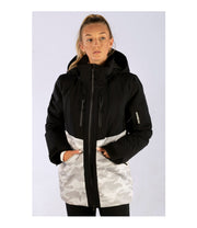 A woman wearing a two-tone insulated jacket with a black hood, shoulders, upper chest, and upper sleeves, paired with a camo pattern body and lower sleeves. The jacket features a front zip closure, two zippered chest pockets, and two side zip pockets, with an adjustable hood.