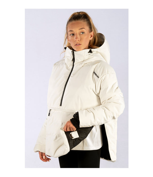A woman wearing a white anorak with a hood, half zip front, a zippered kangaroo pocket and zippered side pockets, and opening up the side zipper.