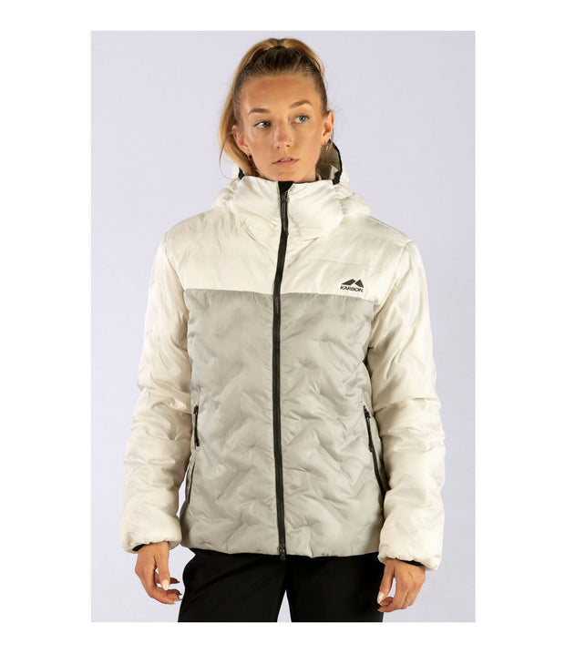 A woman wearing a two-tone puffer with white hood, shoulders, upper chest, and sleeves paired with a beige body. The jacket features welded baffle construction, a front zip closure and two hand zip pockets.